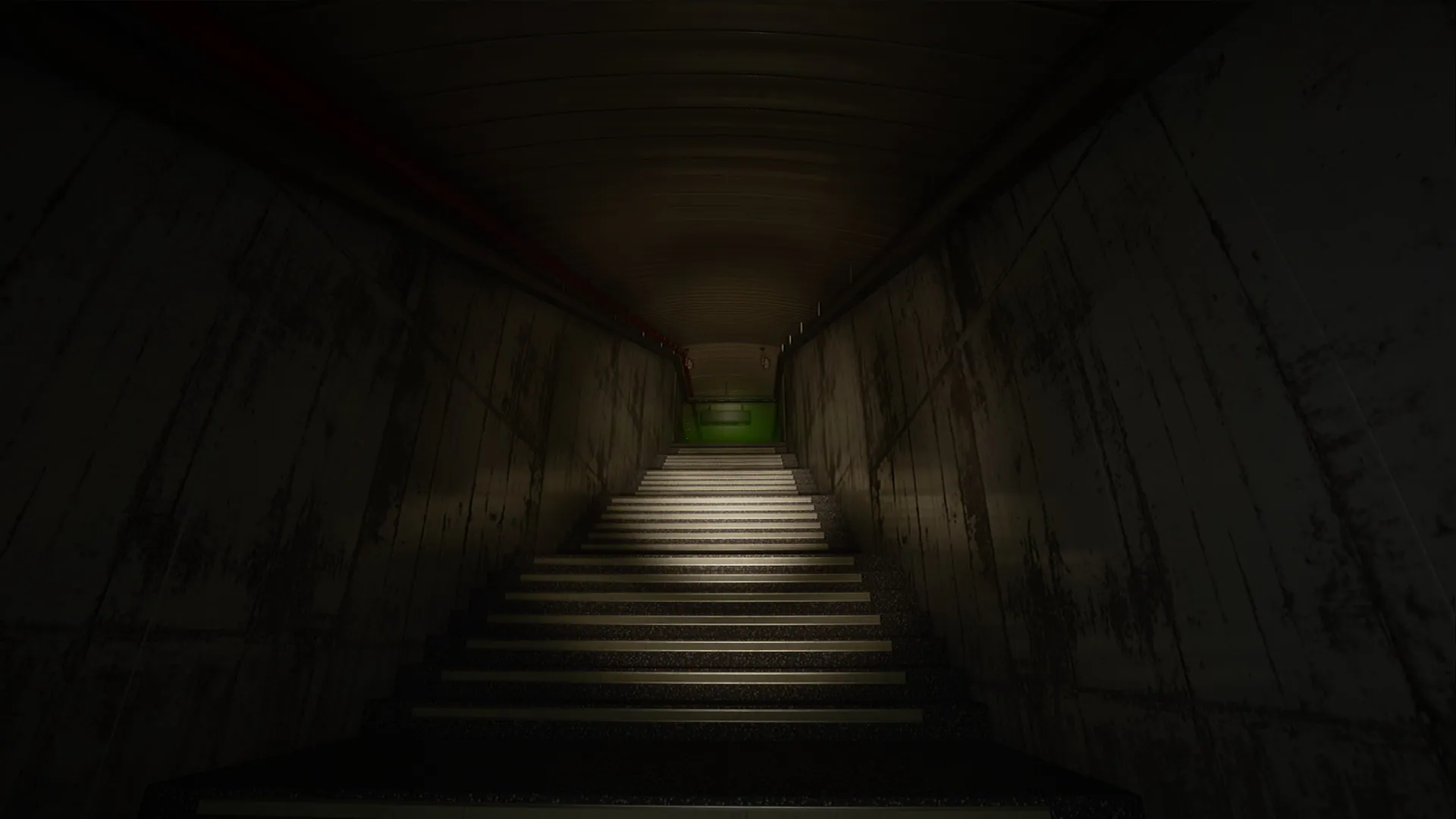 Langer Korridor mit einer Treppe, die hinunter zu einem grünen Notausgangsschild führt